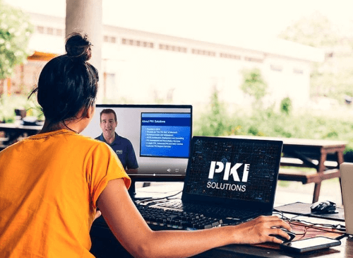 Person sitting at a deck with two monitors doing training on PKI Solutions.
